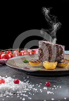 Steak Filet Mignon with Smoke. Baked Potatoes, cranberry Sauce, cherry tomatoes on a gray concrete background