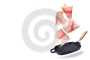 A steak of flying fish falls into the pan. The effect of flying motion in the cooking process.Isolated objects on a white