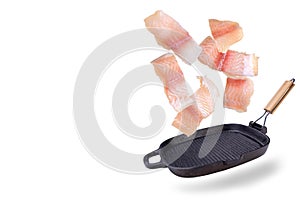 A steak of flying fish falls into the pan. The effect of flying motion in the cooking process.Isolated objects on a