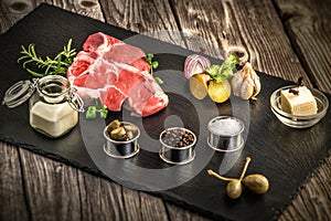 Steak, fresh meat oo stone plate, gastronomy, garlic and onion, spice, rosemary with meat, butter, wood table, additives, preparat