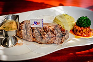 Steak with gravy, mashed potato, salsa on white porecelain plate