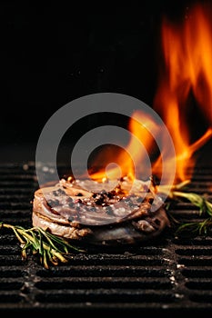 Steak on the grill with flames. raw beef steak on a BBQ grill. banner, menu, recipe place for text, top view