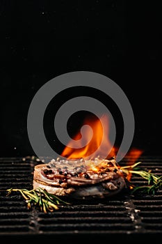 Steak on the grill with flames. raw beef steak on a BBQ grill. vertical image. top view. place for text