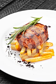 Steak medallion with French fries on a white plate.