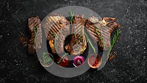 Steak menu. Juicy grilled steaks on a black stone background: t-bone, striploin, Rib eye, new york steak.