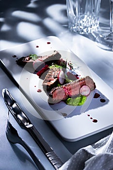 Steak pieces on a dish with pea puree, radish and wine jus