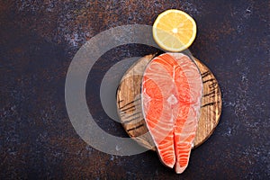 Steak of raw salmon with lemon on a dark background Top view