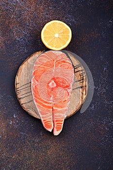 Steak of raw salmon with lemon on a dark background Top view