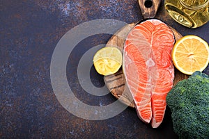 Steak of raw salmon with lemon and olive oil on a dark background Top view