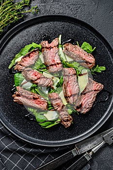 Steak salad with spinach, arugula and sliced beef Striploin steak. Black background. Top view