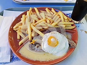 Steak on sauce with egg and fries