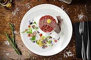 Steak tartare. Horseradish creme, black bread, baguette chips on white plate. Delicious healthy raw meat food closeup