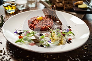 Steak tartare. Horseradish creme, black bread, baguette chips on white plate. Delicious healthy raw meat food closeup