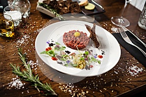 Steak tartare. Horseradish creme, black bread, baguette chips on white plate. Delicious healthy raw meat food closeup