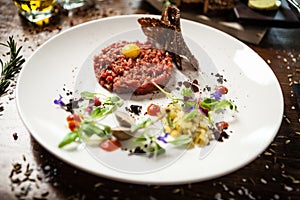 Steak tartare. Horseradish creme, black bread, baguette chips on white plate. Delicious healthy raw meat food closeup