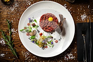 Steak tartare. Horseradish creme, black bread, baguette chips on white plate. Delicious healthy raw meat food closeup