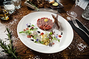 Steak tartare. Horseradish creme, black bread, baguette chips on white plate. Delicious healthy raw meat food closeup