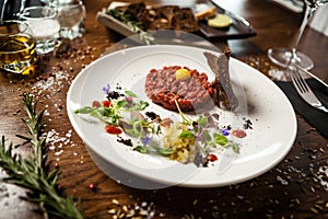 Steak tartare. Horseradish creme, black bread, baguette chips on white plate. Delicious healthy raw meat food closeup