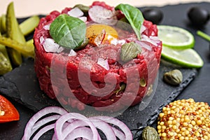 Steak tartare of raw minced meat with salt and spices, on a black stone