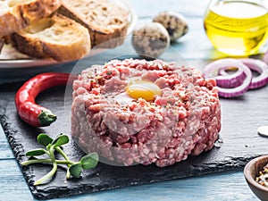 Steak tartare served with raw quail egg yolk, chilly pepper and bread. Meat dish