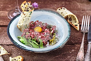Steak tartare served with raw quail egg yolk and other tartare ingredient. Meat dish.