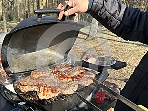 Steaks being cooked on the grill, close-up. A man cooks meat on a gas grill. Cooking outdoors, picnic