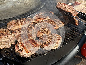 Steaks being cooked on the grill, close-up. A man cooks meat on a gas grill. Cooking outdoors, picnic