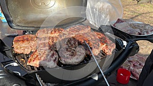 Steaks being cooked on the grill, close-up. A man cooks meat on a gas grill. Cooking outdoors, picnic