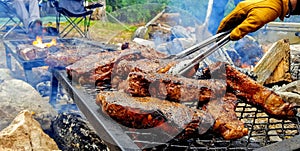 Steaks on the grill with yellow gloves and tong camping grilling barbeque
