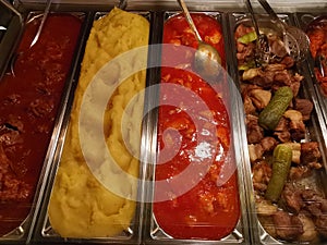 Steaks, polenta and sauces in stainless steel trays