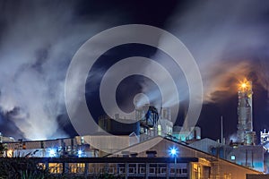 Steam billows from a pulp and paper mill at night