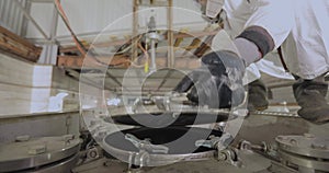 Steam cleaning station. A worker in chemical protection at a steam cleaning station for tanks for liquid cargo