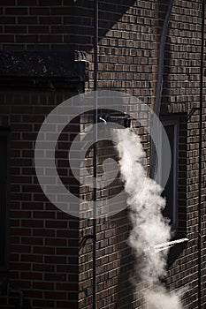 Steam coming out of a central heating flue on a house wall in South Korea photo