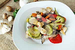 Steam-cooked chicken with vegetables on rustic deco with garlic, mushrooms and green leaves