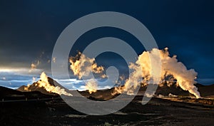 Steam erupting from geothermal power station at sunset photo