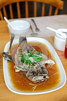 steam fried Marbled Goby fish called Ikan Malas in siamese style served in a dish on a wooden table in a restaurant in Indonesia