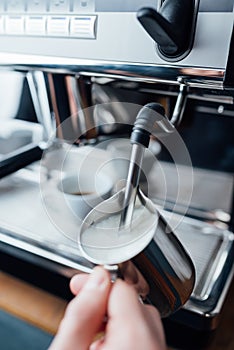 Steam frothing milk under pressure from a coffee machine in pitcher