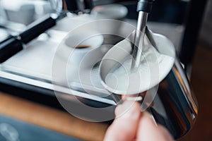 Steam frothing milk under pressure from a coffee machine in pitcher