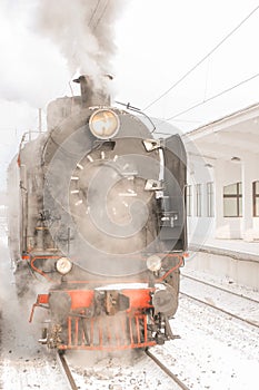 Steam locomotive in clouds of smoke on the platform photo