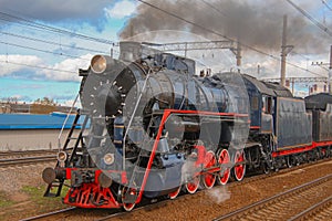 Steam locomotive in clouds of smoke rides on the railway photo
