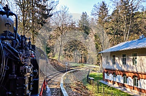 Steam locomotive drives past a house in the forest. Dynamic due to motion blur