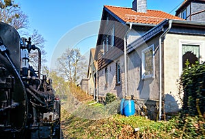 Steam locomotive drives past the houses. Dynamic through motion blur