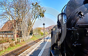 Steam locomotive drives through the streets of the city of Wernigerode past the houses. Dynamic through motion blur