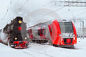 Steam locomotive and modern multiple-unit train stand nearby at station