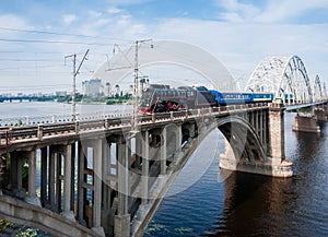 Steam locomotive with passenger train in motion on bridge