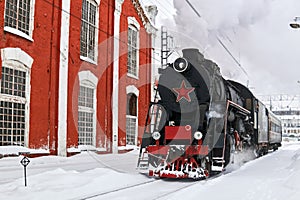 Steam locomotive passing through train station in winter