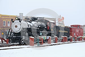 A steam locomotive sits in the snow covered small town