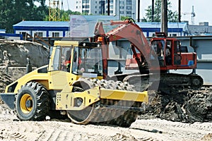 Steam roller and excavator on construction site