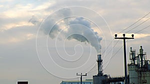 Steam and smoke coming out of a factory chimney against a cloudy sky. Air pollution concept, emissions, station, climate change,