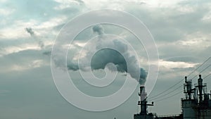 Steam and smoke coming out of a factory chimney against a cloudy sky. Air pollution concept, emissions, station, climate change,